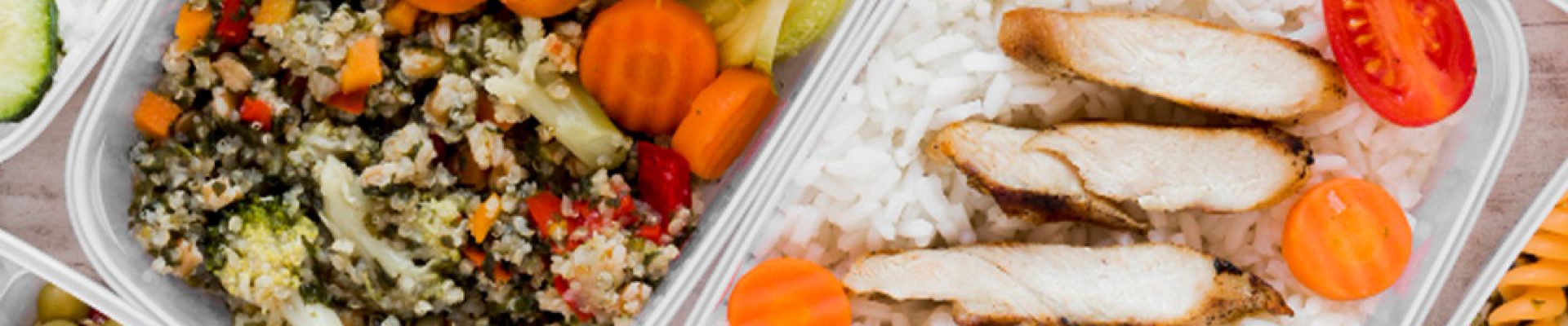 Mehrere Meal‑Prep‑Boxen mit gesunden Zutaten: eine mit Weißreis, in Streifen geschnittener gegrillter Hähnchenbrust, Karottenscheiben und Cherrytomaten; andere mit spiralisierten Zucchini und einem halben gekochten Ei, Quinoa‑Gemüse‑Mischung, Salaten, Oliven, Mais und Kiwischeiben.